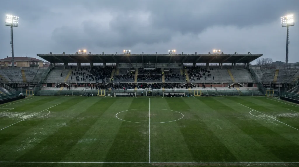 Stadio di calcio semivuoto con tribune in ombra, atmosfera malinconica di fine stagione
